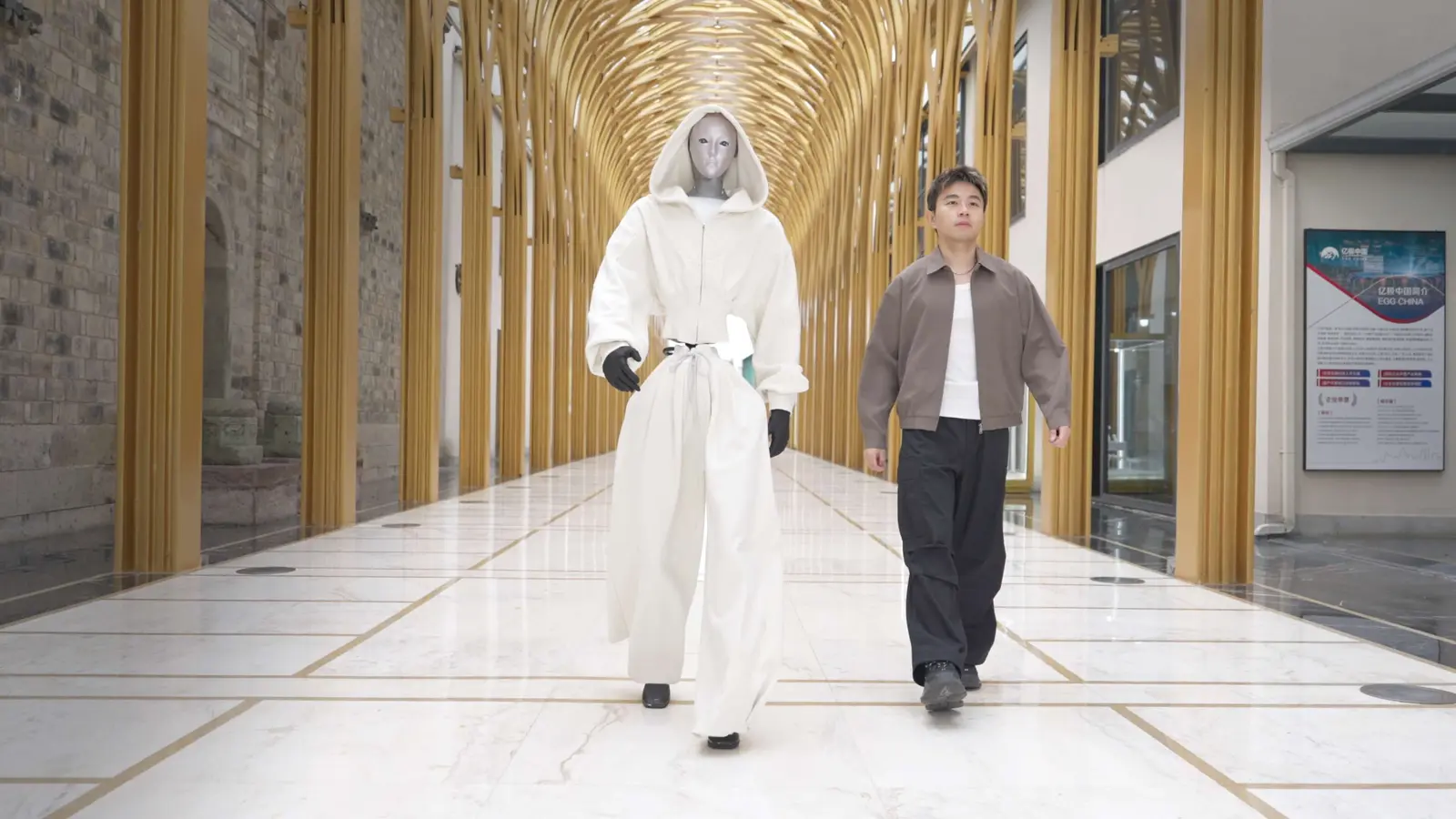 Robot humanoïde Unitree H2 marchant dans un espace public sous supervision humaine